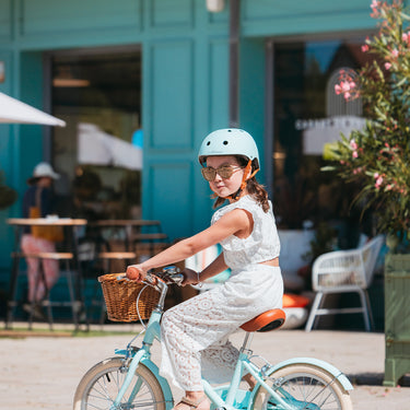 Fille de 6 ans portant le casque vélo BeBikeen XS bleu turquoise, assorti à son vélo Bebikeen.