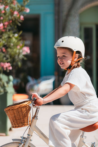 Fille portant le casque vélo enfant BeBikeen XS crème, 2 à 6 ans, sur vélo 16 pouces crème, vue de profil gauche.