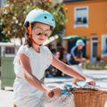 Fille de 6 ans porte le casque vélo BeBikeen XS turquoise, assorti à son vélo bleu turquoise Bebikeen.