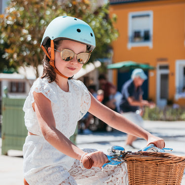 Fille de 6 ans porte le casque vélo BeBikeen XS turquoise, assorti à son vélo bleu turquoise Bebikeen.