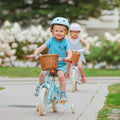 Garçon de 3 ans sur vélo Bebikeen 12 pouces bleu turquoise avec panier avant en osier naturel et casque bleu turquoise assorti.