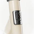 Macaron métallique de la marque française BeBikeen apposé sur le cadre crème intemporel, signature d’un design soigné et d’une fabrication pensée pour durer.