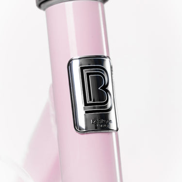 Macaron métallique de la marque française BeBikeen apposé sur le cadre rose délicat, signature d’un design soigné et d’une fabrication pensée pour durer.