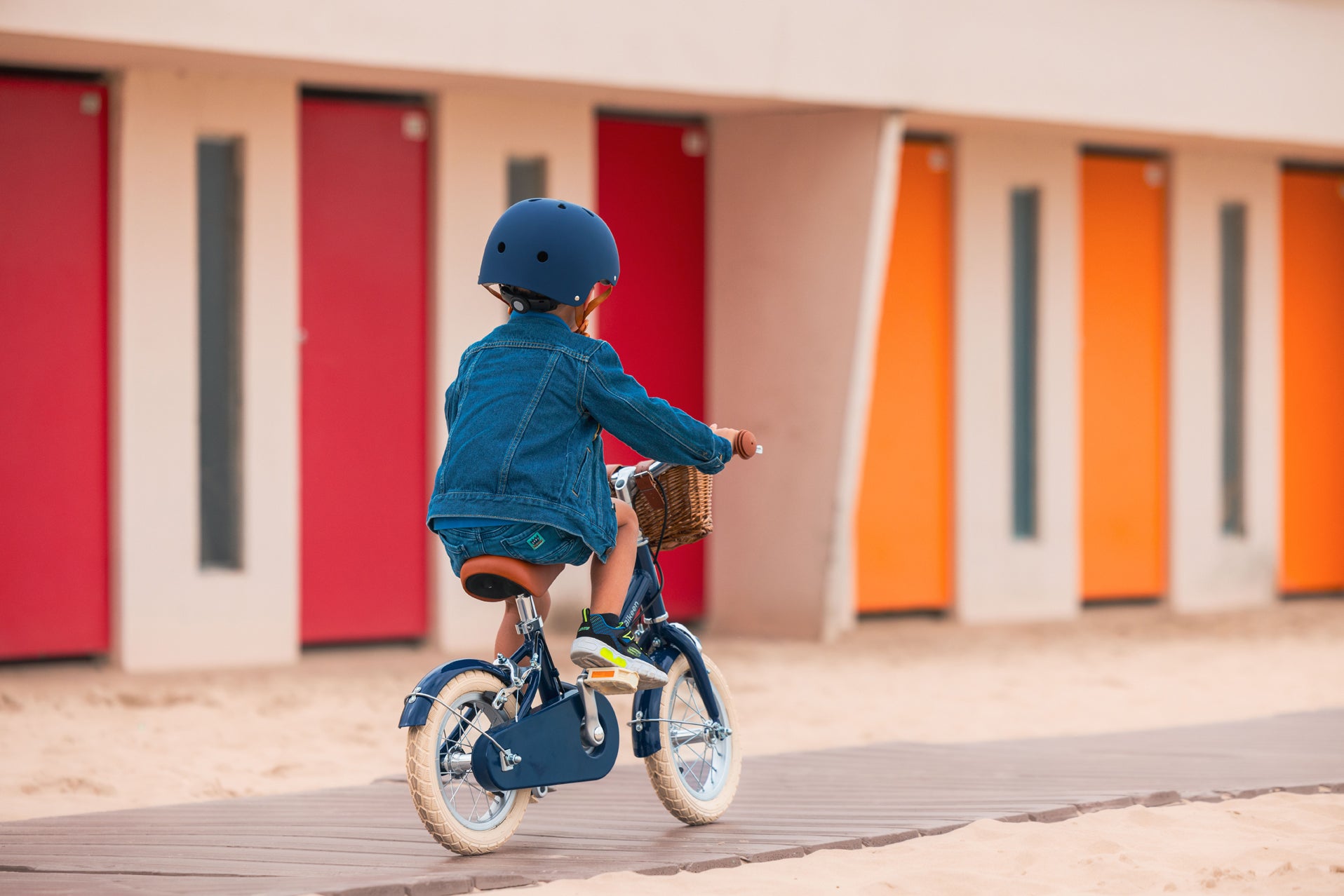 Garçon portant un casque bleu marine Bebikeen, pédale sur son élégant vélo enfant 12 pouces bleu marine avec selle marron, photo prise au Touquet.