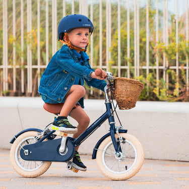Garçon de 3 ans roule joyeusement sur vélo Bebikeen 12 pouces bleu marine, 2 à 4 ans, avec casque assorti.