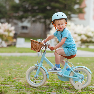 Garçon de 3 ans roule dans un jardin sur le vélo Bebikeen léger 12 pouces bleu turquoise lumineux, adapté aux 2 à 4 ans.