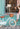 Fille de 6 ans assise à côté de son vélo léger Bebikeen 16 pouces bleu turquoise avec panier en osier et béquille, portant un casque bleu turquoise assorti.