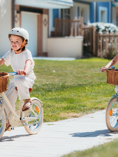 Deux filles  en promenade à vélo Bebikeen 16 pouces, bleu turquoise et crème, adaptés aux enfants de 4 à 6 ans avec leur casque assorti.