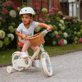 Fille de 3 ans roule avec aisance sur son vélo Bebikeen 12 pouces crème léger, 2 à 4 ans, avec stabilisateurs, dans une allée de jardin.