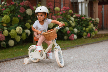 Fille de 3 ans roule avec aisance sur son vélo Bebikeen 12 pouces crème léger, 2 à 4 ans, avec stabilisateurs, dans une allée de jardin.