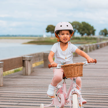 Fille de 3 ans sur vélo Bebikeen 12 pouces léger, rose, 2 à 4 ans, vue de face avec panier et casque assorti.