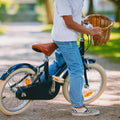Vélo léger enfant Bebikeen 16 pouces bleu marine, 4 à 6 ans, avec selle marron en simili cuir et panier en osier naturel.