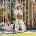 Fille de 5 ans à côté de son vélo enfant Bebikeen 16 pouces crème léger, 4 à 6 ans, avec béquille et selle marron en simili cuir.