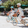 Fille de 5 ans pédale sur vélo enfant Bebikeen 16 pouces crème léger, avec selle marron en simili cuir et panier en osier naturel.