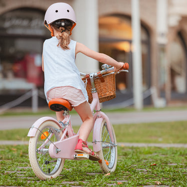 Fille de 5 ans vue de dos sur vélo léger Bebikeen 16 pouces rose, pour enfant de 4 à 6 ans, avec casque rose assorti.