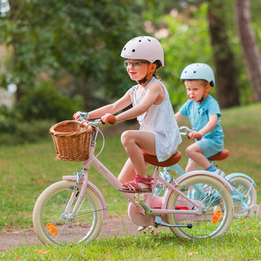 Frère et sœur pédalent sur vélos Bebikeen, fille sur le 16 pouces rose léger avec casque assorti, garçon sur vélo bleu, profil.
